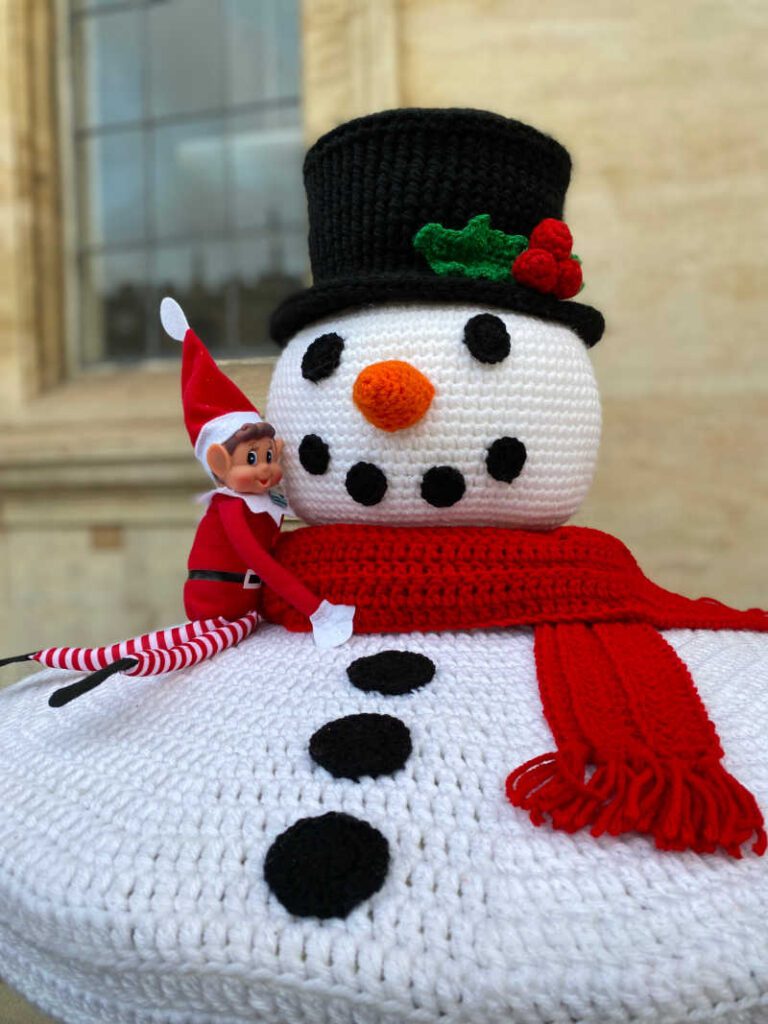 Elf sitting on a snowman crocheted post box topper