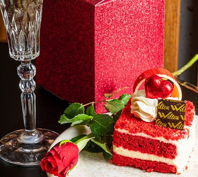 A glass of Prosecco a rose and slice of red velvet cake