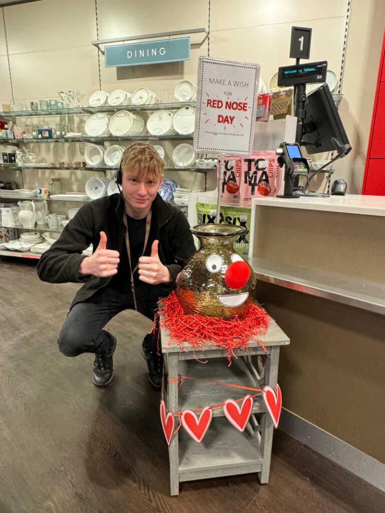 Man kneeling down in front of a red nose day display in TK Maxx