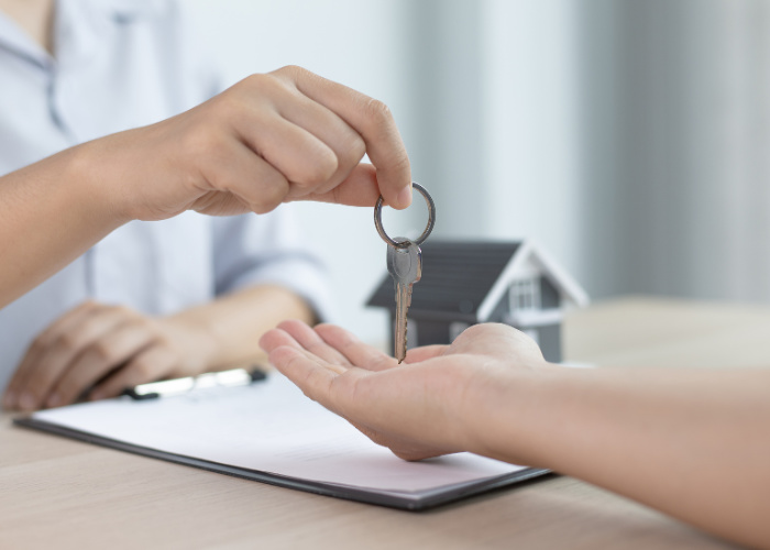 Two hands holding keys to a house