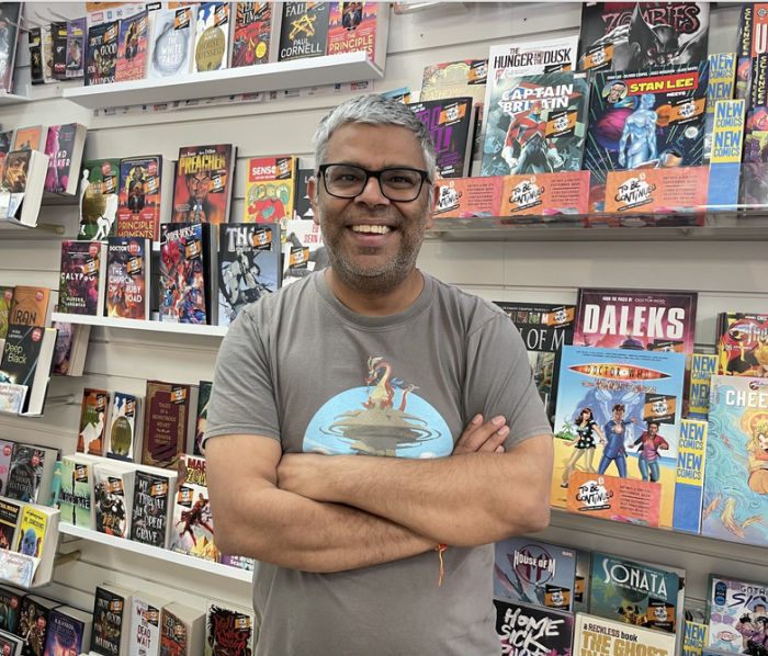 A man standing in front of a wall filled with comics at Close Encounters. 