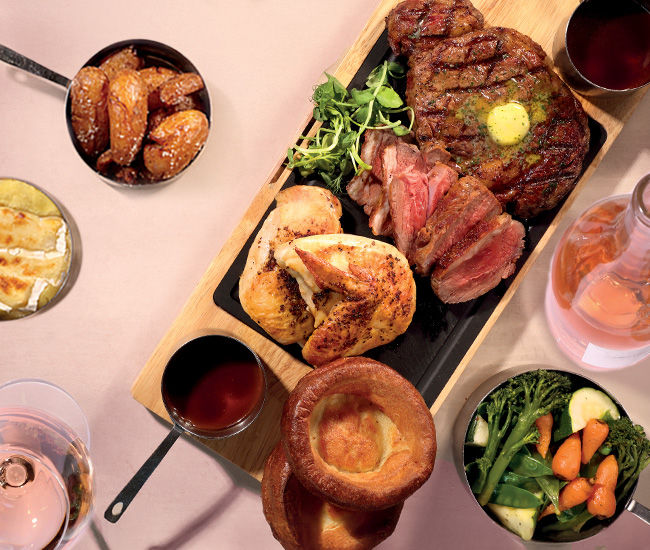 A table loaded with sunday roast dishes including roast beef, carrots and yorkshire pudding