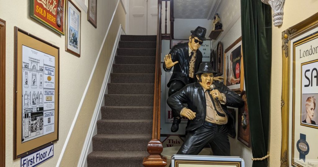 staircase entrance with framed pictures lining the walls and a large blues brothers statue next to the staircase.
