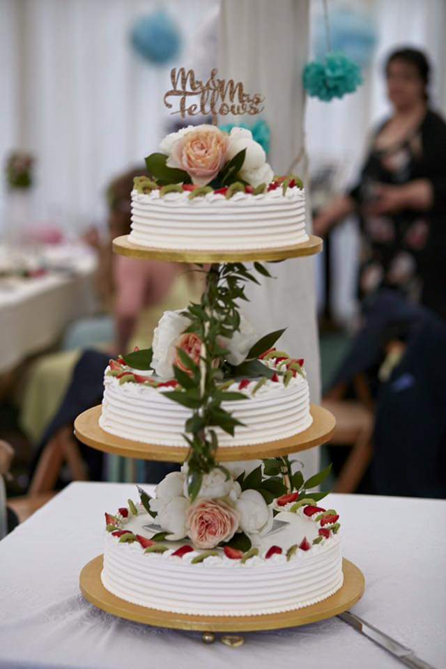 Three seperate tier cake on a display stand decorated with flowers
