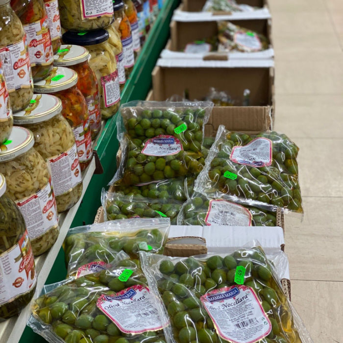 Produce on display packaged olives and jarred peppers.
