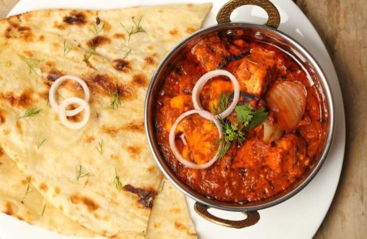 Curry in a bowl and naan bread on a plate