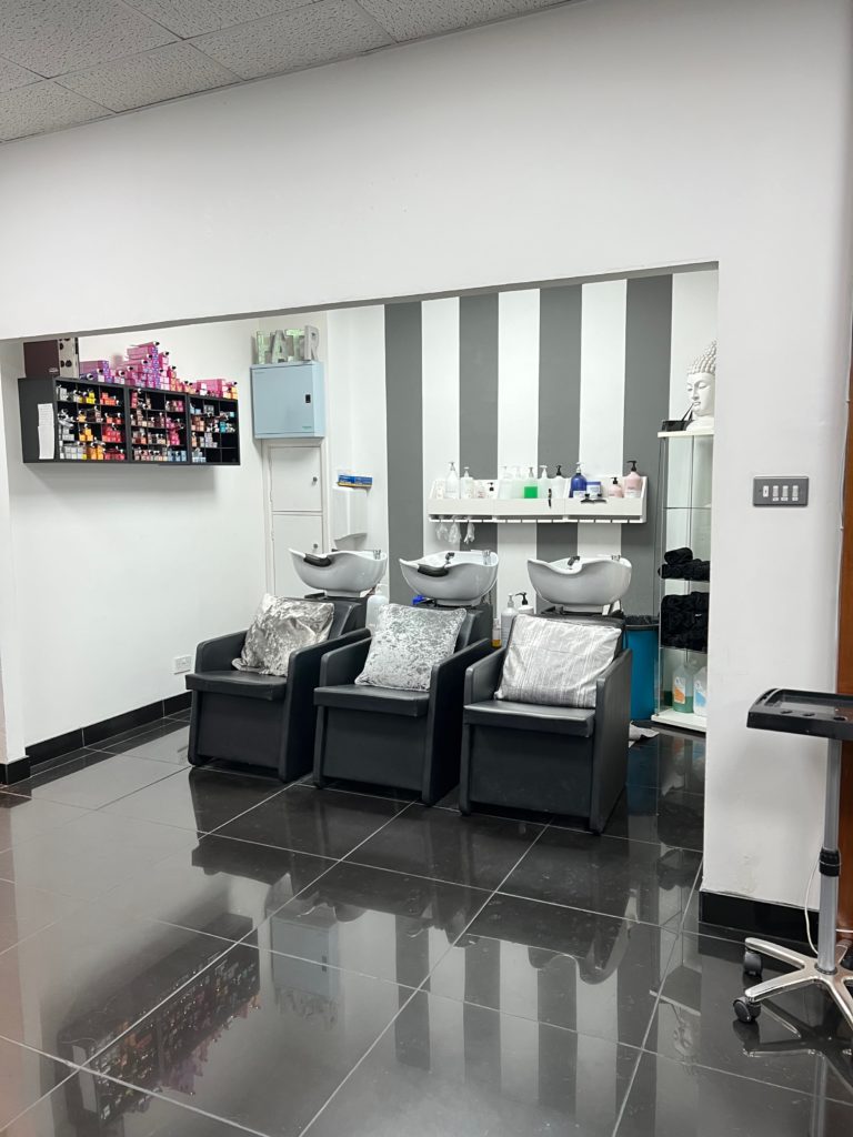 3 cushioned seats with 3 hair washing stations behind in a row.