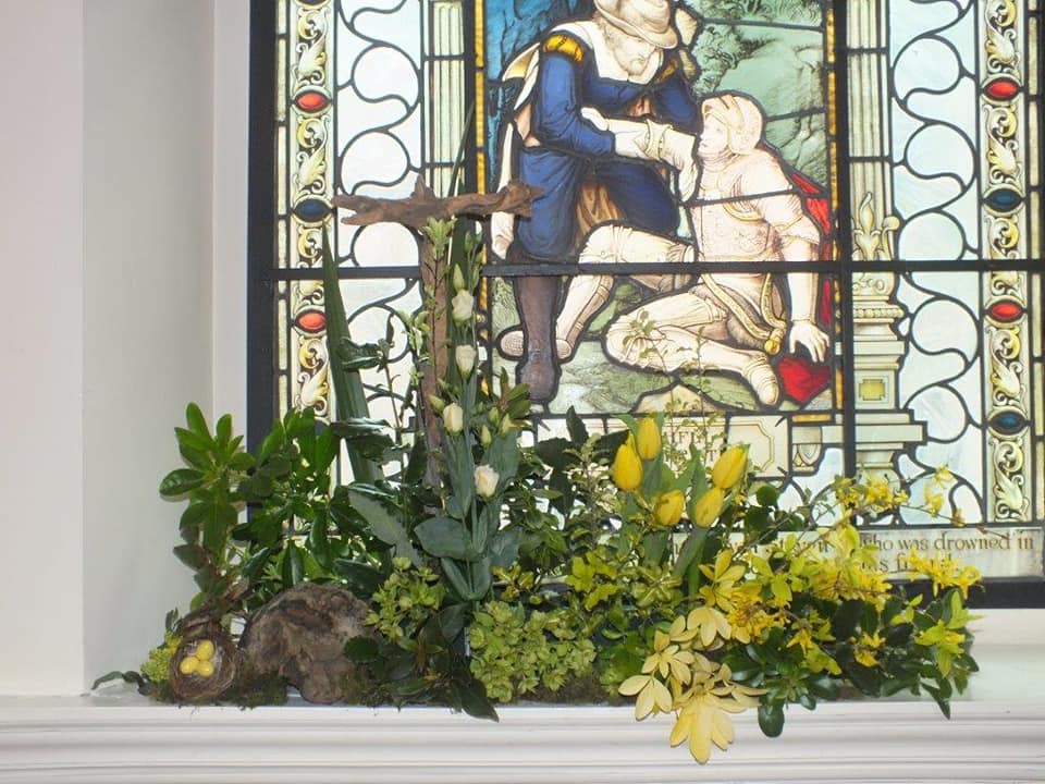 Yellow flowers and green plant in front of a stained glass window