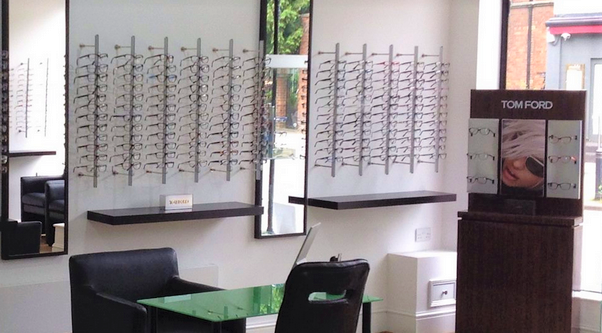 Alan Brunker shop with hooks of glasses, mirrors, seats, consultation desk and advertising boards