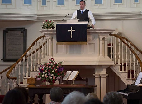 Preacher stood in pulpit addressing congregation.