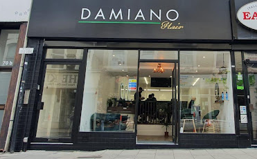 Damiano Hair shopfront with white, green and gold logo on black background