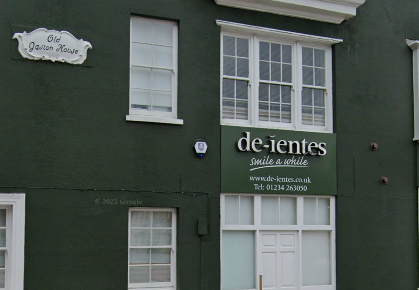 De-ientes dark green building with white doors, windows and logo