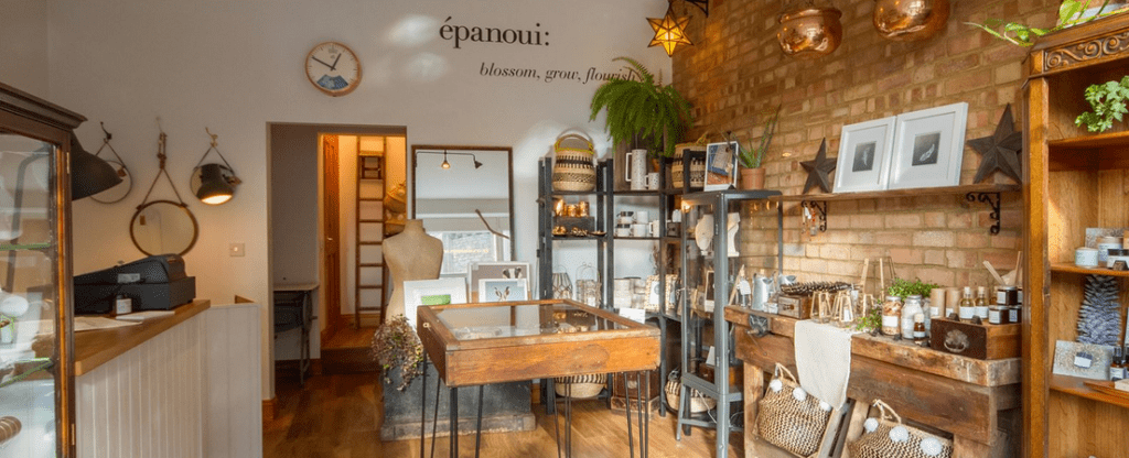 Epanoui shop interior with exposed brick walls, products on wooden shelves, with wooden display cabinets showing jewellery