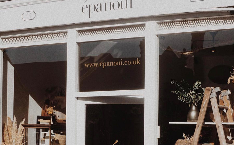 Epanoui shopfront with pale and dark grey boarding with large glass windows with products displayed