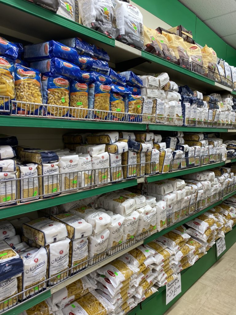 A large variety of pasta displayed on several shelves in store.