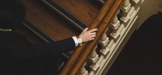 Longstaff image of person in a suit and nice watch walking up stairs holding bannister