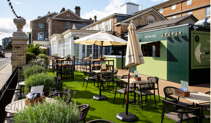 Pen & Cob Terrace with artificial grass, tables, chairs, umbrellas and bar
