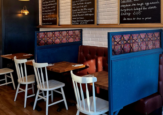 Roosters indoor seating with blue dividers, wooden tables and white chairs