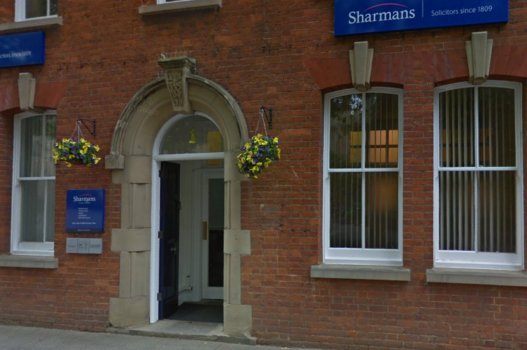 Sharman front of office historic brick building with blue and white signage