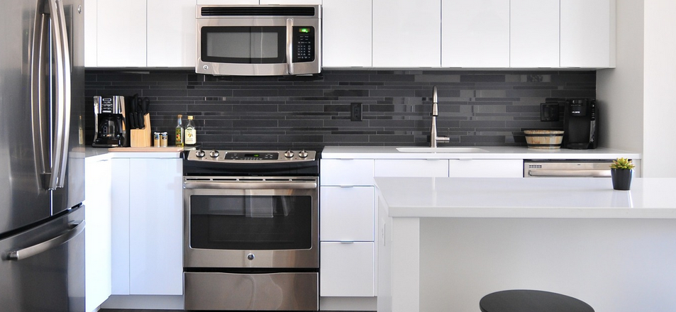Wilson Peacock new kitchen, white modern cabinets and dark grey tiles behind sink