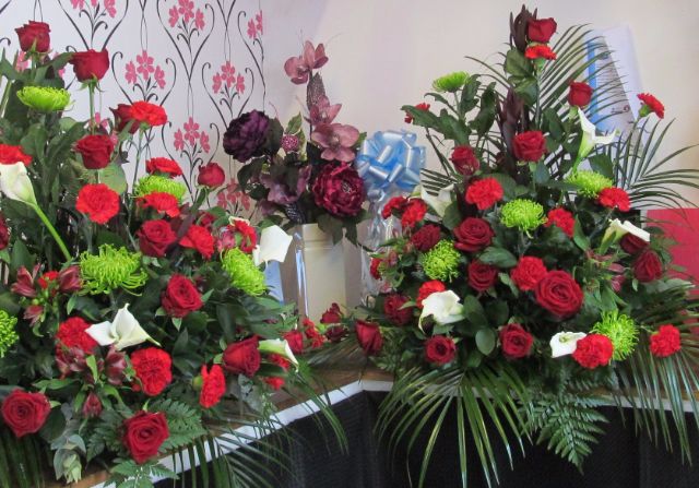 Large bouquets with red, burgundy, white and green flowers with palm and fern dressing.