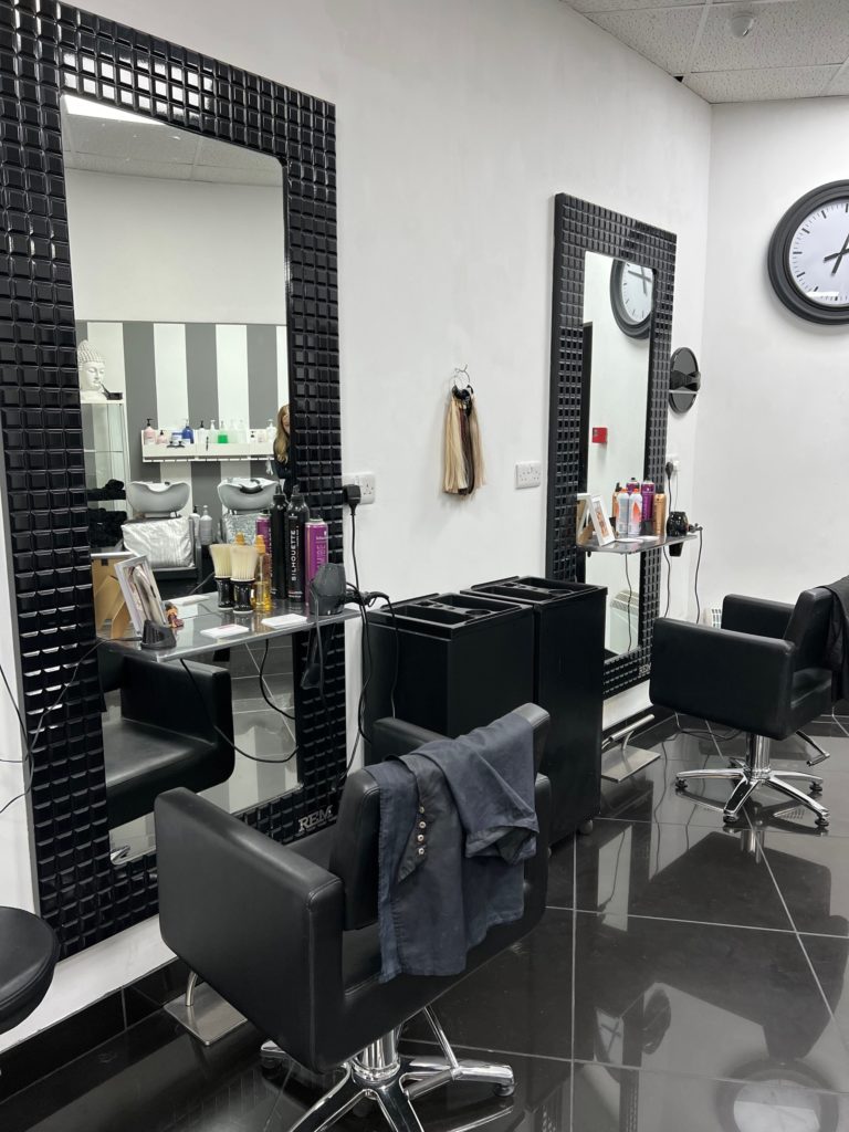 hairdressers black chair in front of a large black framed mirror