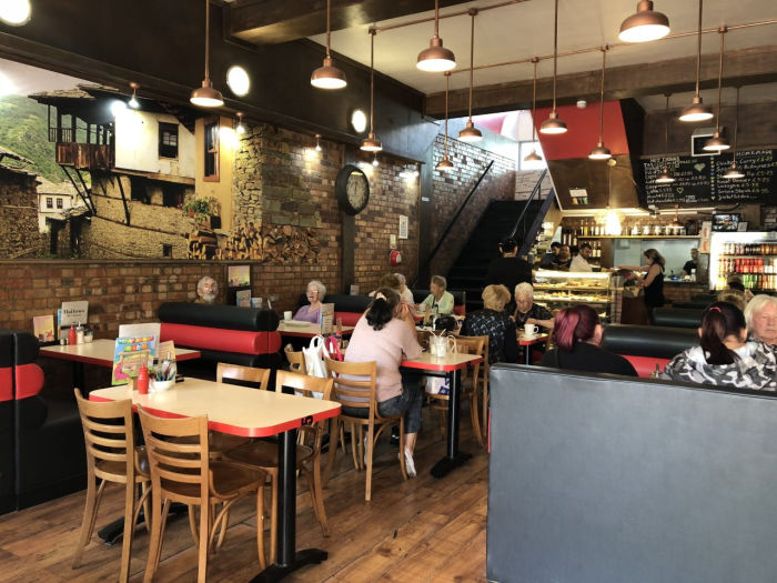 Hallows Cafe interior with exposed brick walls, wooden tables and chairs with people dining