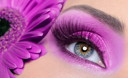 Instyle image on ladies blue eye with vivid purple makeup, lovely lashes and brow with a similar colour flower