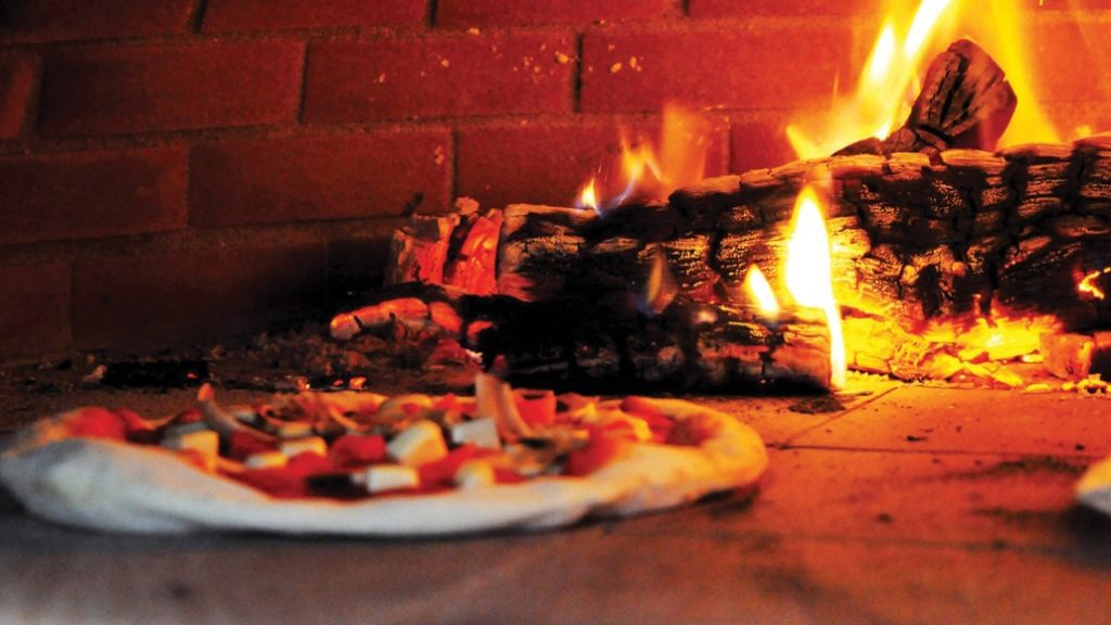 Pizza in Pizza over, wooden logs on fire behind