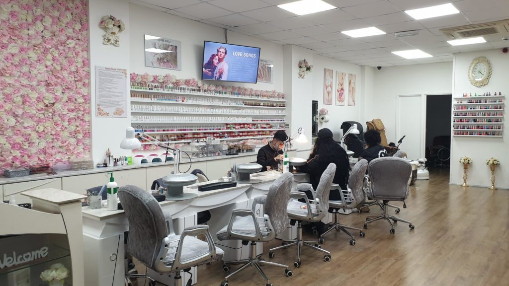 Lisa's Nails shop interior with pink flower wall and customer having nails done