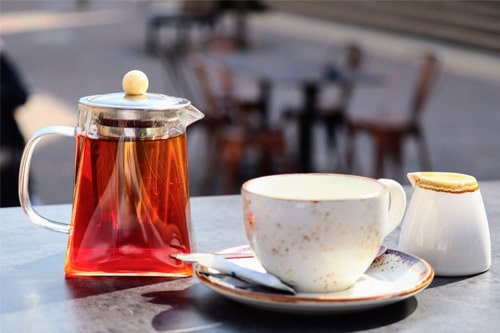 Cafe table with clear glass tea pot with earthenware cup and saucer