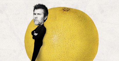 Rhod Gilbert comedian leaning against a giant grapefruit