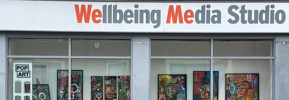 Wellbeing Media banner of shopfront with orange and grey wording