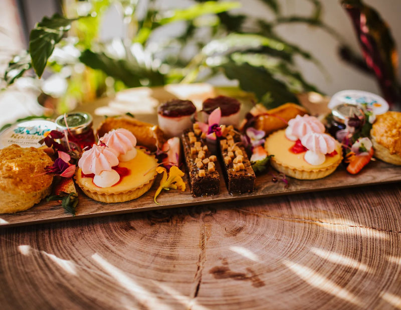 A wooden platter containing pretty cakes and pastries.