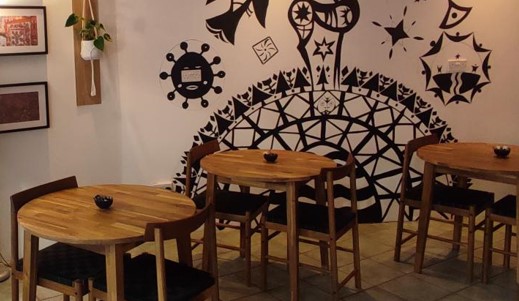 Chairs and round tables in a cafe environment with a mural on the wall.