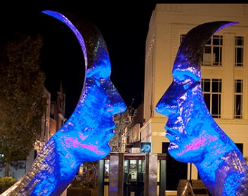 The Silver Faces statue lit up in blue.