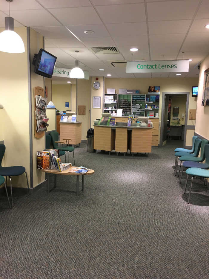 Inside Specsavers Bedford with chars and a waiting area and sign saying contact lenses.