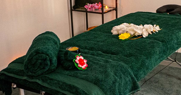 Jade Buddha Spa massage table with flowers and dark green towels