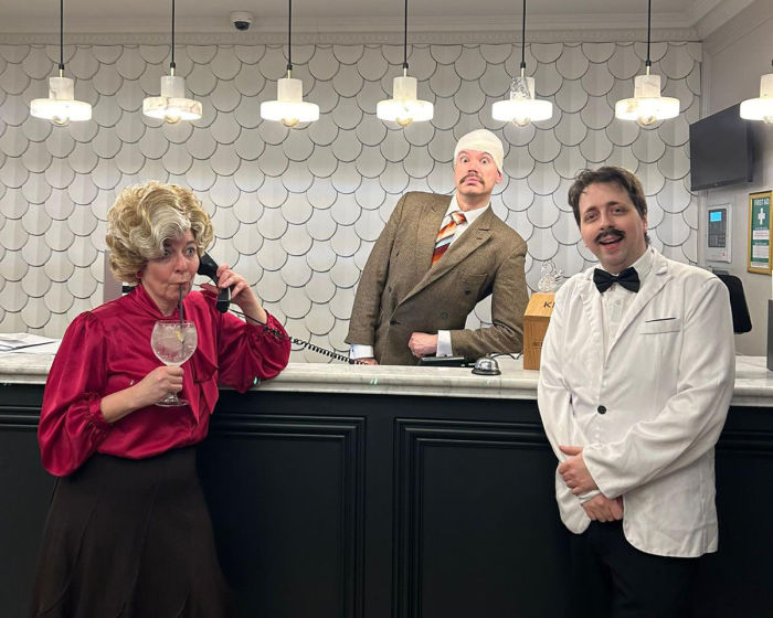 Faulty Towers image of three people at the reception in Bedford Swan Hotel